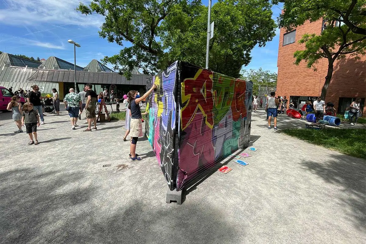 Kinder besprühen beim Bürgerfest West in Stuttgart-West eine Wand mit bunten Graffiti-Buchstaben