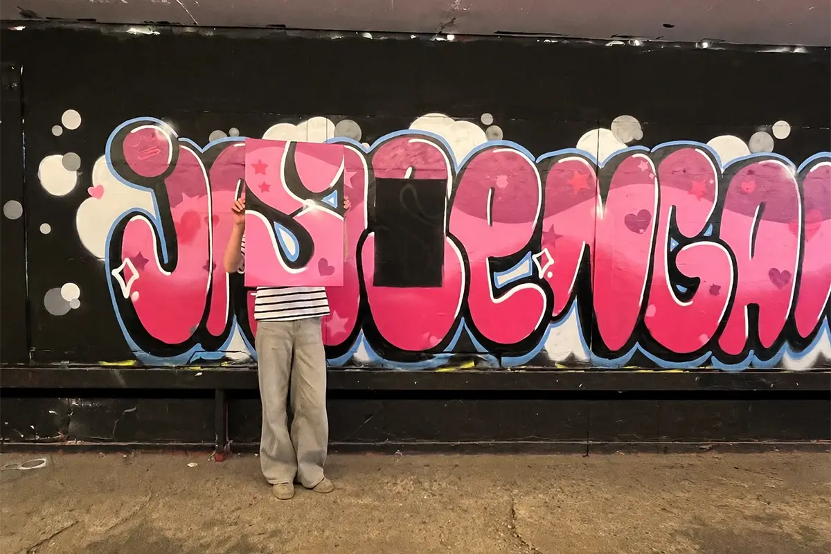 Kind hält eine selbst gestaltete Graffiti-Leinwand im Format 40 × 60 cm vor einer bemalten Wand im High Five Stuttgart.