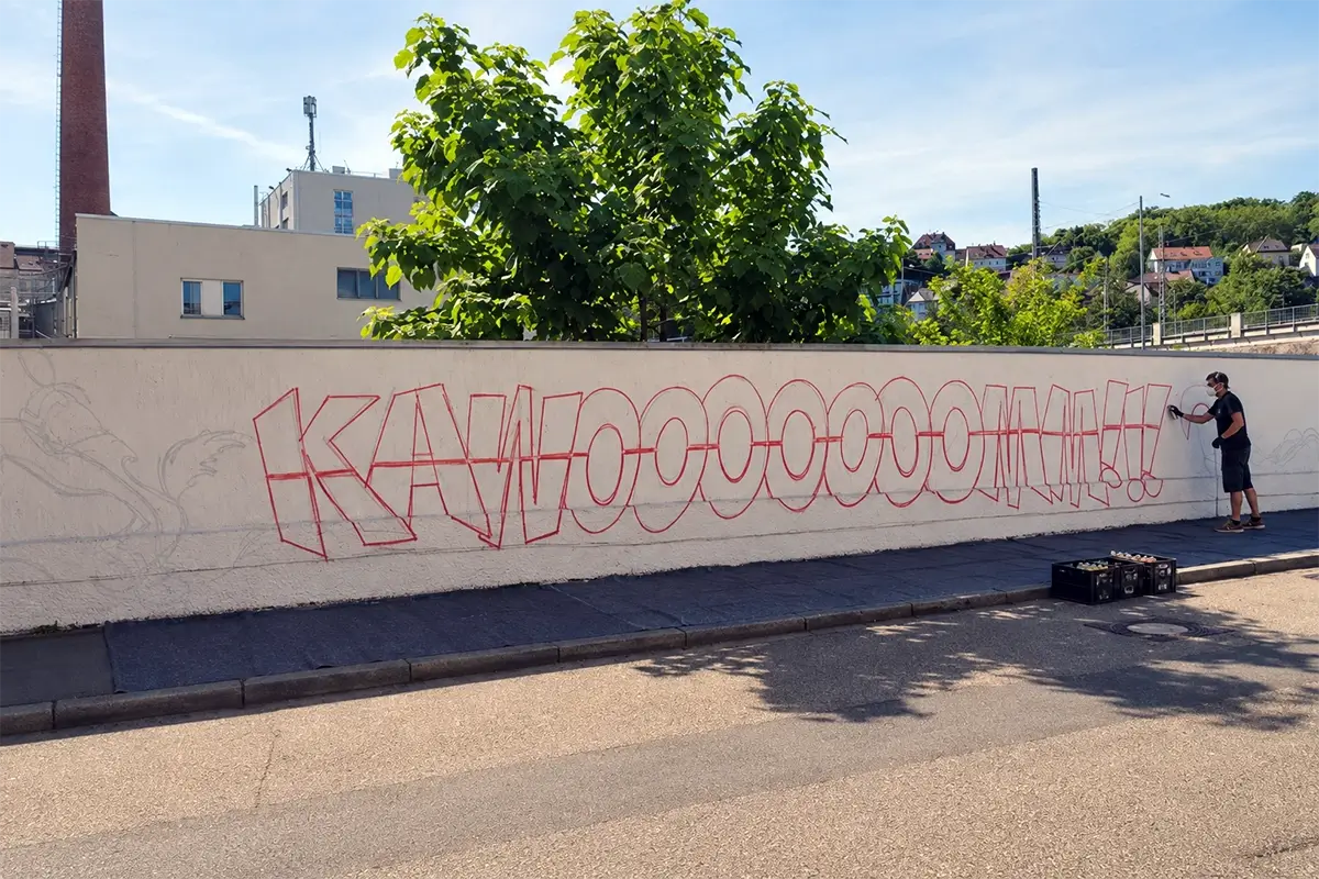 Vorbereitete Betonwand mit vorgezeichnetem Graffiti-Motiv, Malervlies und Sprühdosenkisten für eine Graffiti-Aktion vor Ort.