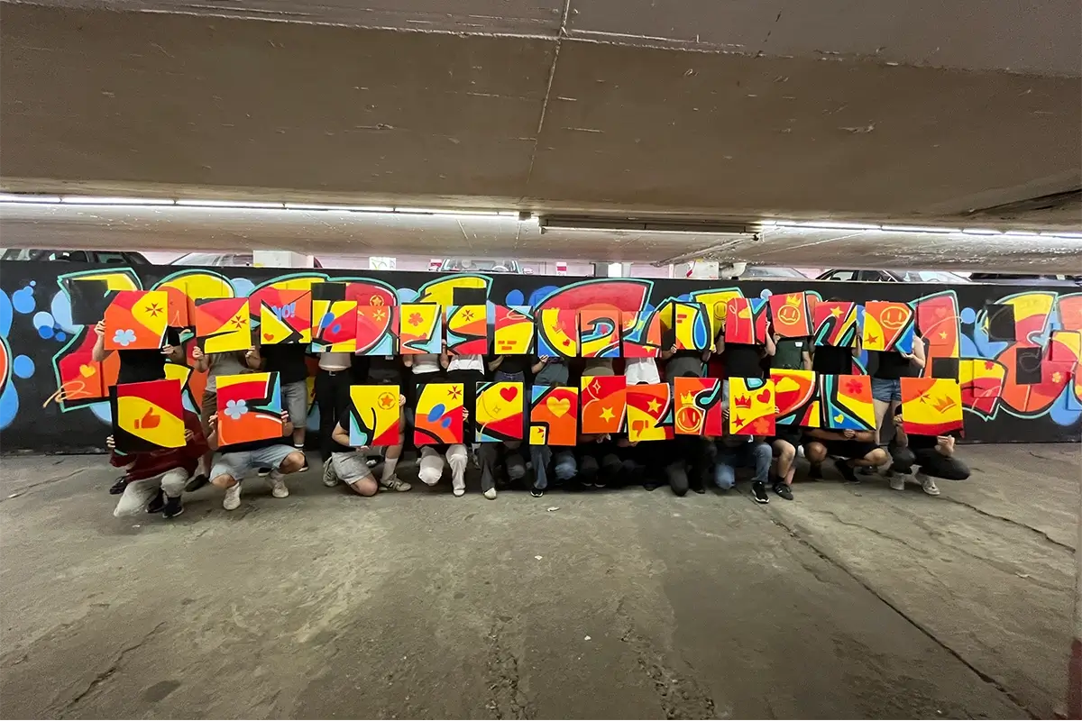Firmenevent mit der Johanniter-Unfall-Hilfe in Stuttgart: FSJler:innen sprühen gemeinsam den Schriftzug „Aus Liebe zum Leben" und nehmen ihre Leinwand mit.